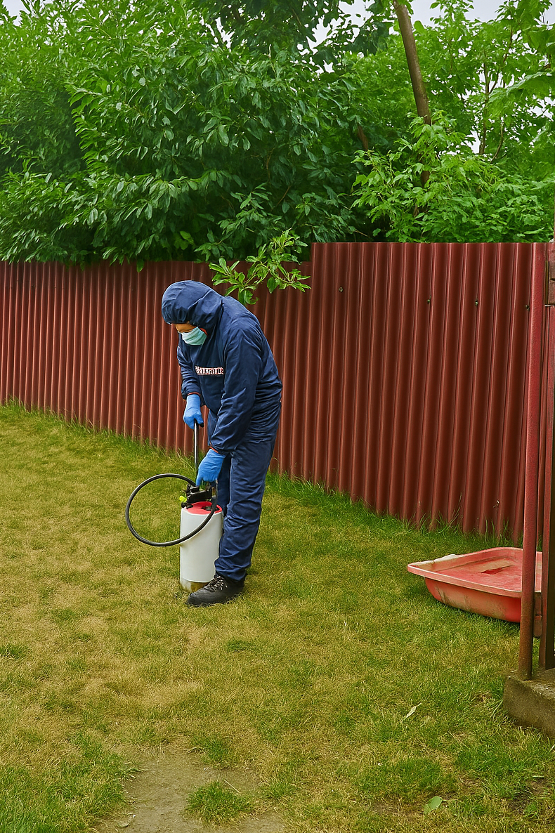 technicien Deratisenet dans un jardin en tenu pour détruire un nid de guêpes